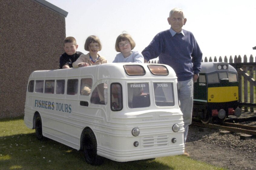 Three young children sit inside a miniature bus, joined by Matt Kerr of Kerr's Miniature Railway