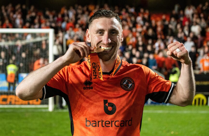Dundee United's Louis Moult bites in to his Championship medal