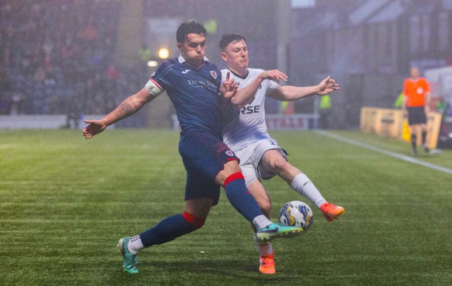 Dylan Corr in action for Raith Rovers against Ross County as he tackles George Harmon.