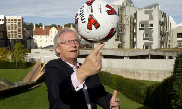 Former First Minister Henry McLeish spins a football on his finger.