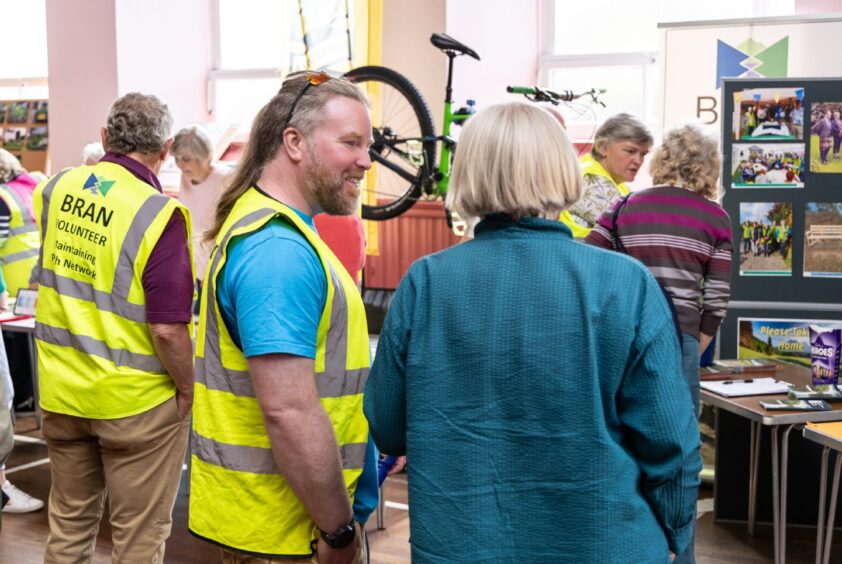 Woman talking to man with long hair and hi vis jacket next to stand with a mountain bike display