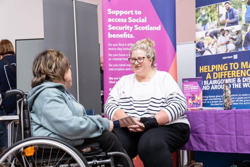 Two women in wheelchairs chatting next to a stall