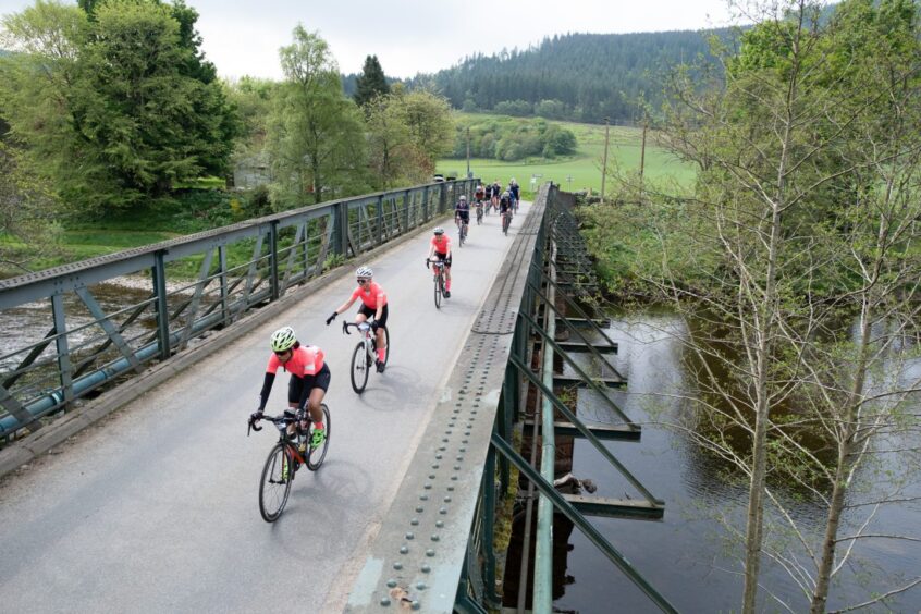 Cyclists crossing metal bridge over river