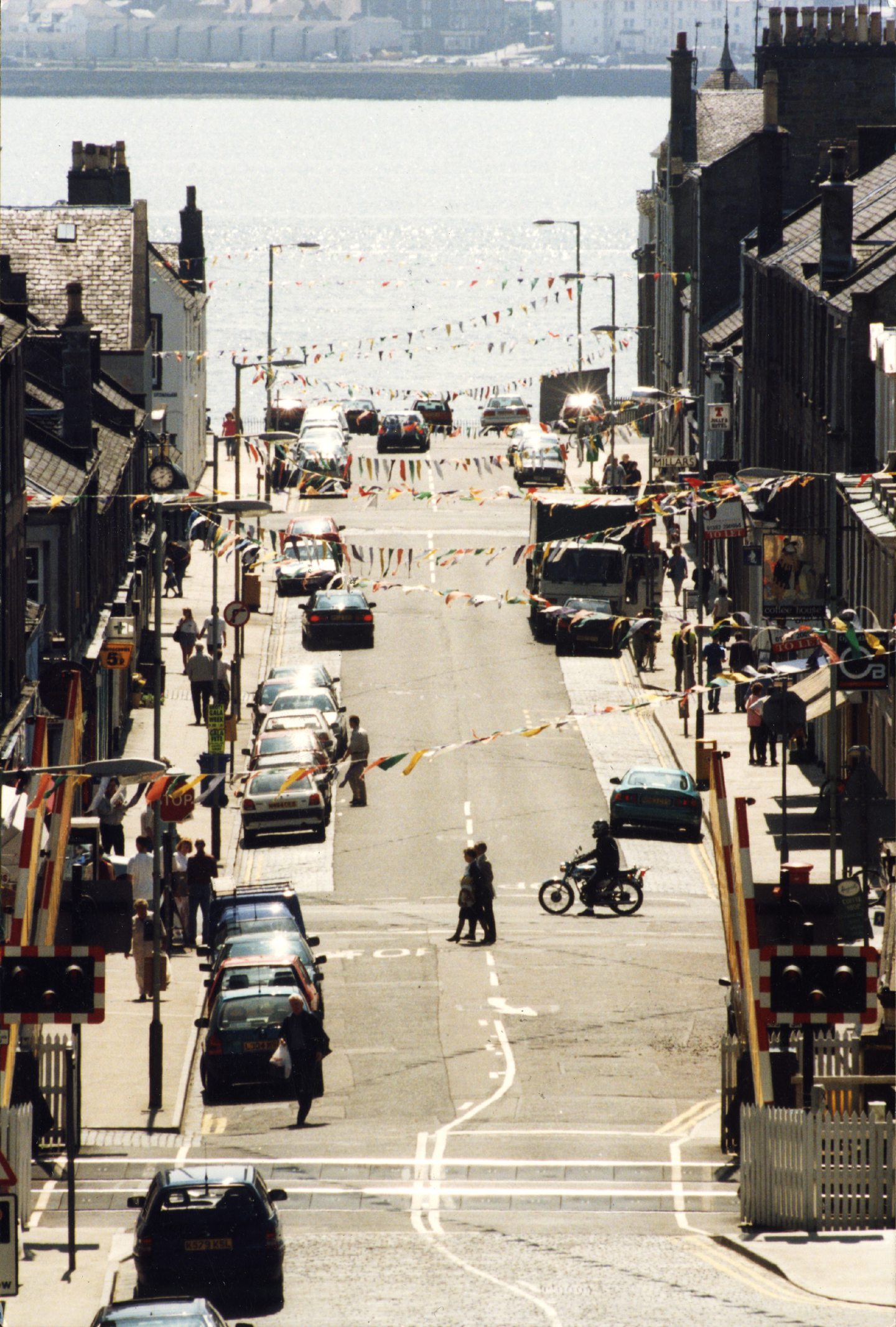 An aerial view looking down the street in June 1996, with bunting hanging from buildings and the River Tay in the background