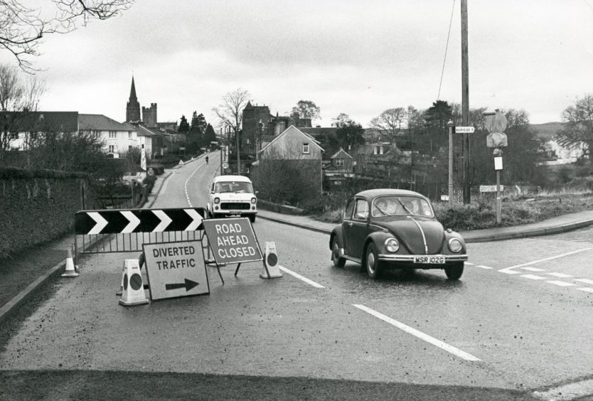 Two cars make their way past a sign at an Invergowrie road closure in 1978.
