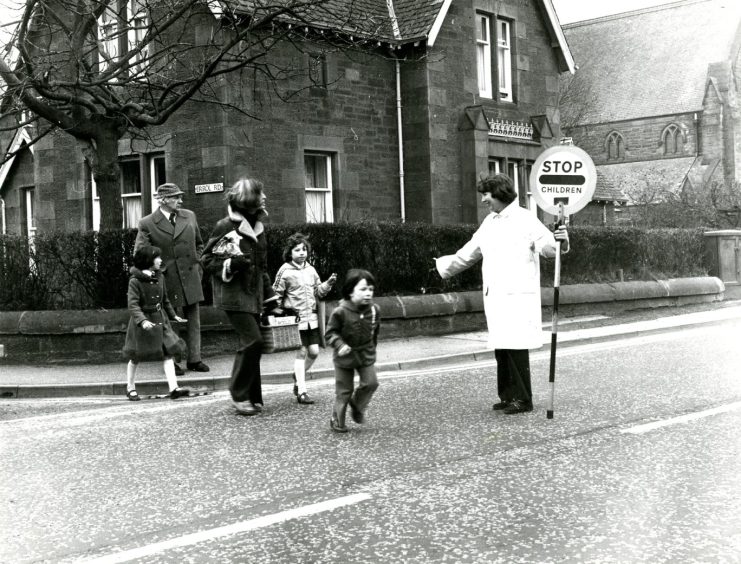 Lollipop lady Mrs McCabe helps children and adults across the road on her final day in March 1978. 