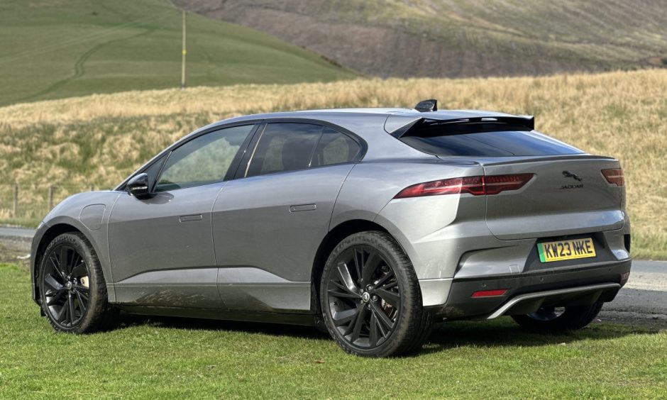 A side/rear view of the Jaguar with fields in the background