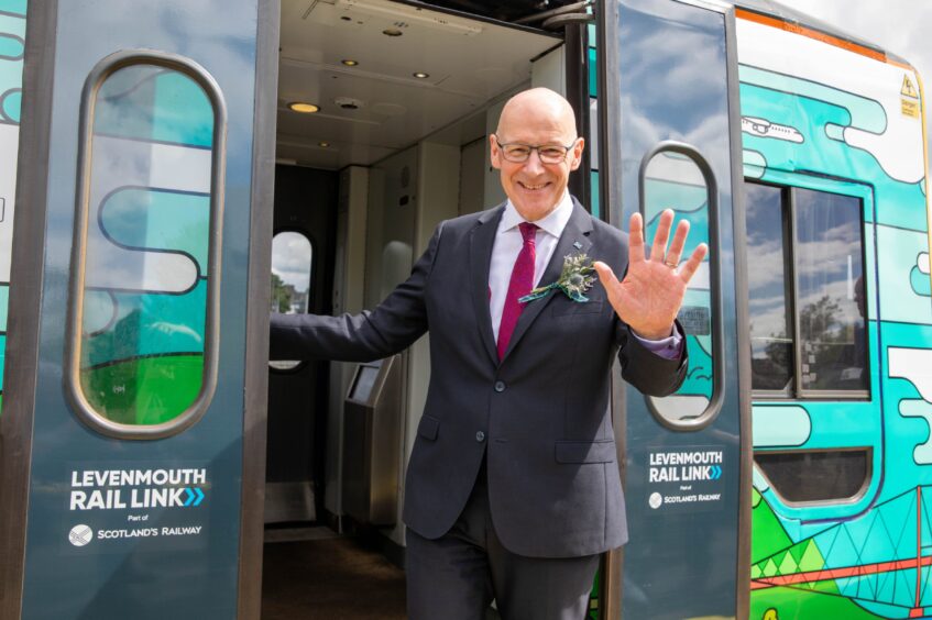 First Minister John Swinney leans out of the first train to run on the new Levenmouth rail link