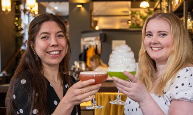Two women clinking their cocktail glasses together.