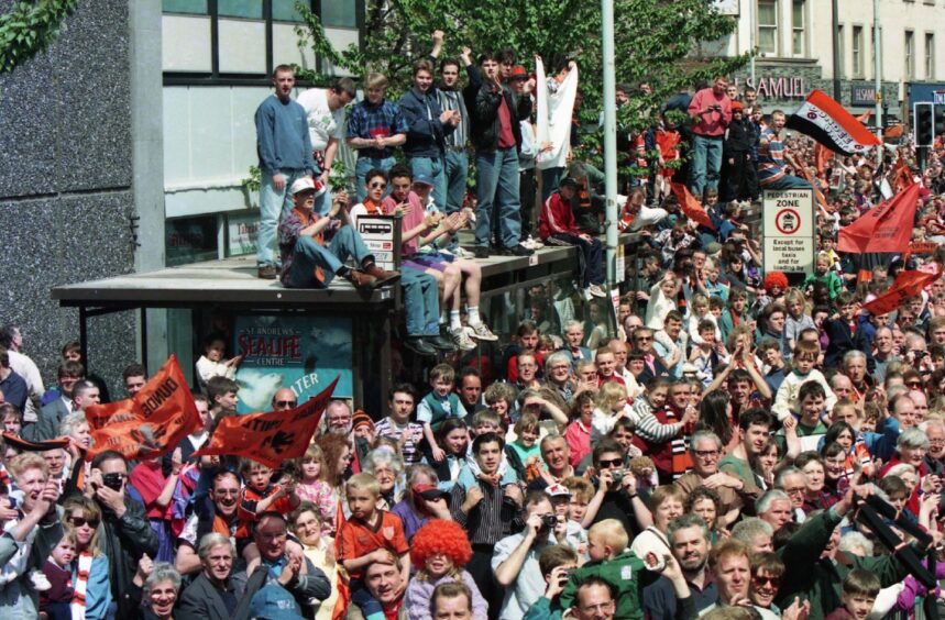 United fans take up every vantage point available, including on top of a bus stop