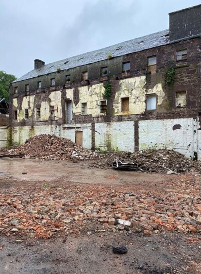The dilapidated Old Mill, which had lain empty for 25 years, with piles of rubble beside it.