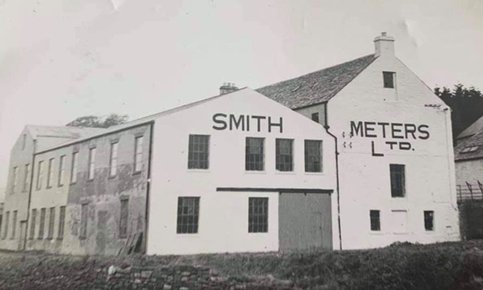 A black and white picture showing how the Old Mill originally looked. Smith Meters Ltd is painted on the side of the building.