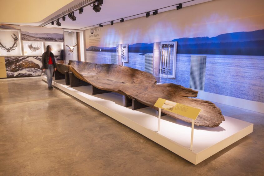 Person walking past large boat carved from a single log in Perth Museum