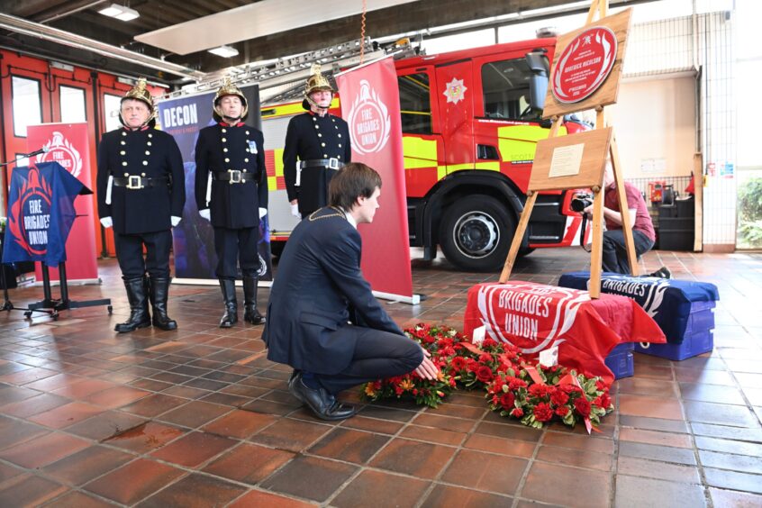 Perth and Kinross Provost Xander McDade lays a wreath in front of Roderick Nicolson's plaque, watched by firefighters in vintage uniforms