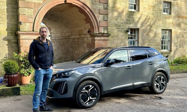 Motoring writer Jack McKeown stands beside the Peugeot e-2008
