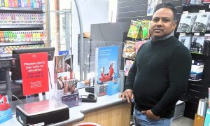 Aberfeldy post master Seenithamby Sujeevan standing next to his post office counter