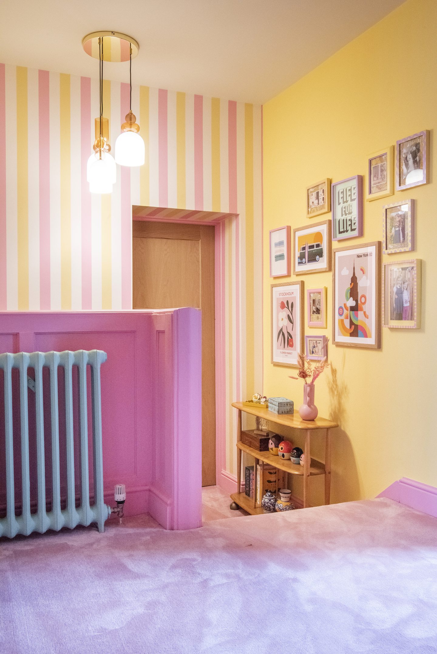 The landing of the house, with yellow and pink walls, which is full of vintage and mid-century furniture. 