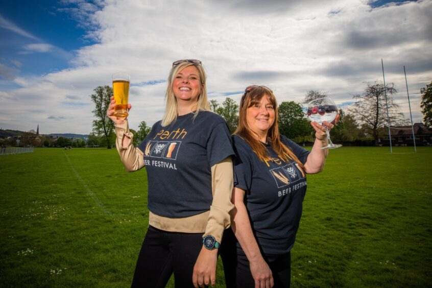 Perth Beer Festival organisers Natalie MacKinnon and Carol Ann Rose in festival t shirts holding a pint glass and a gin glass at the North Inch, Perth