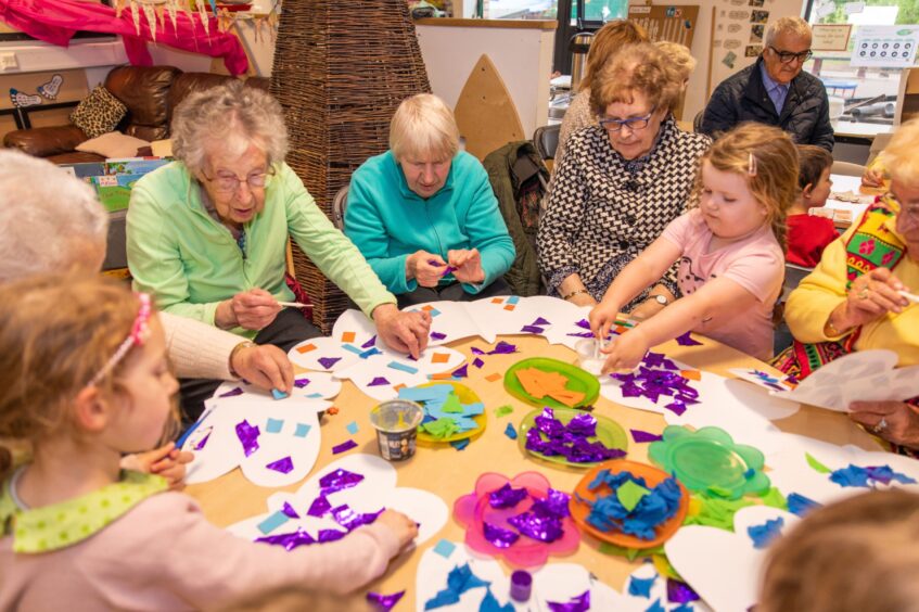 Older women making paper butterflies with little girls