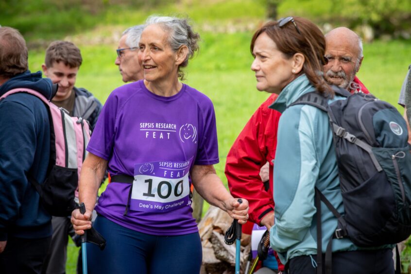 Dee Thomas in purple sepsis research t shirt among a group of friends in walking gear