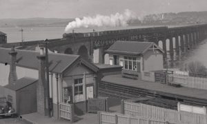 Wormit Station with a goods train going over the Tay Bridge in the background.