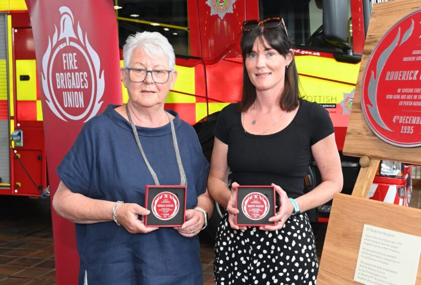 Yvonne Nicolson and daughter Amy Russell holding red plagues in front of fire engine