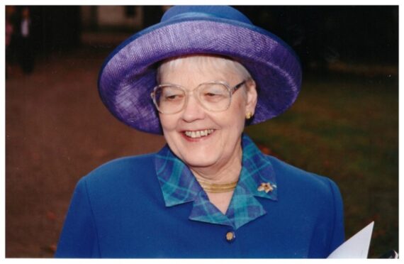 Elizabeth McDiarmid smiling in smart blue outfit and hat