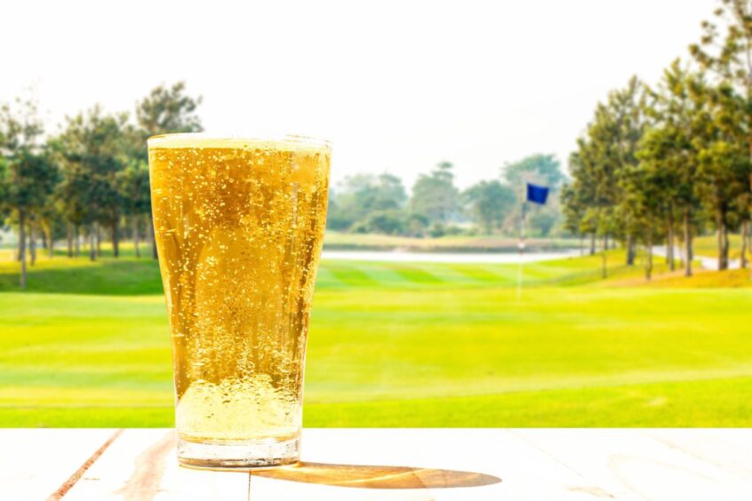 Glass of beer on the background blur of golf course.