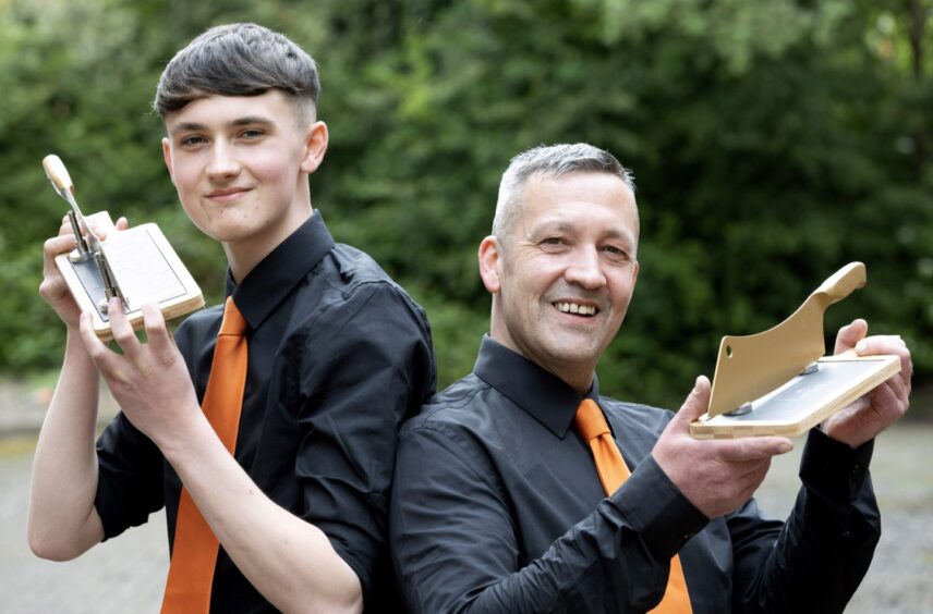 Ben and Richard Megahy holding Butcher Wars trophy, in shape of a knife on a chopping block