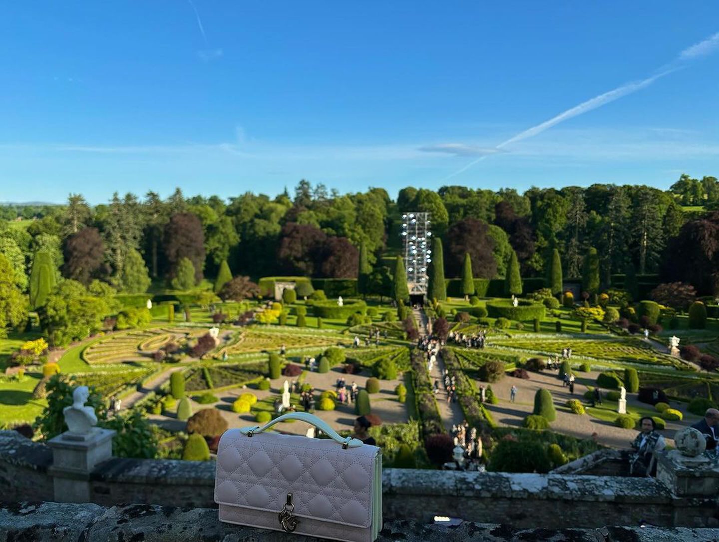 A picture of a Dior purse, with Drummond Castle gardens in the background.