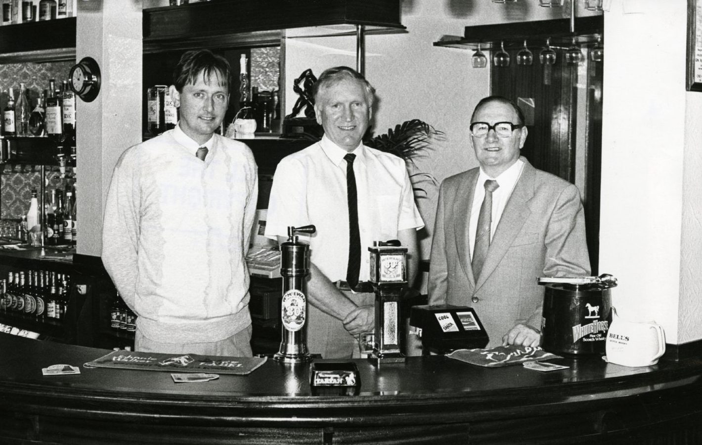 George Kidd Junior, Ron MacLaughlan and George Kidd behind the bar in the Ellenbank Bar in 1986