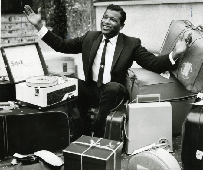 Sugar Ray Robinson - wearing a suit and surrounded by luggage - after he arrived in Scotland in August 1964.