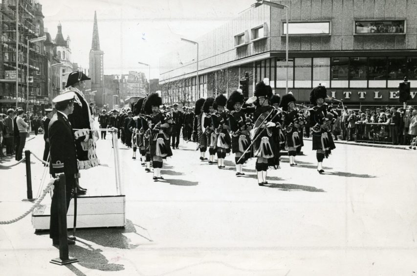 Lord Provost Harry Vaughan takes a salute at City Square in April 1980 as the parade, led by a pipe band, passes by.