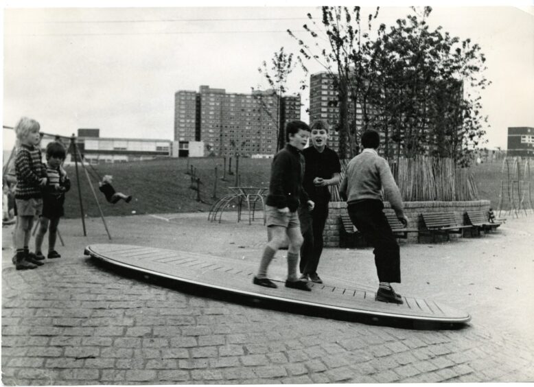 A group of young boys playing on the turntable in a Whitfield playpark in August 1972