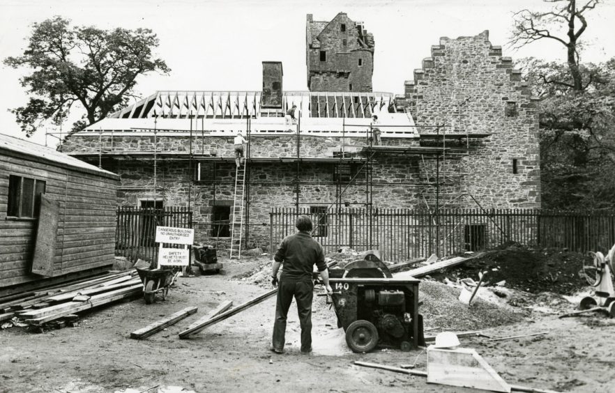 Mains Castle restoration work, with a man standing in the yard surrounded by building materials