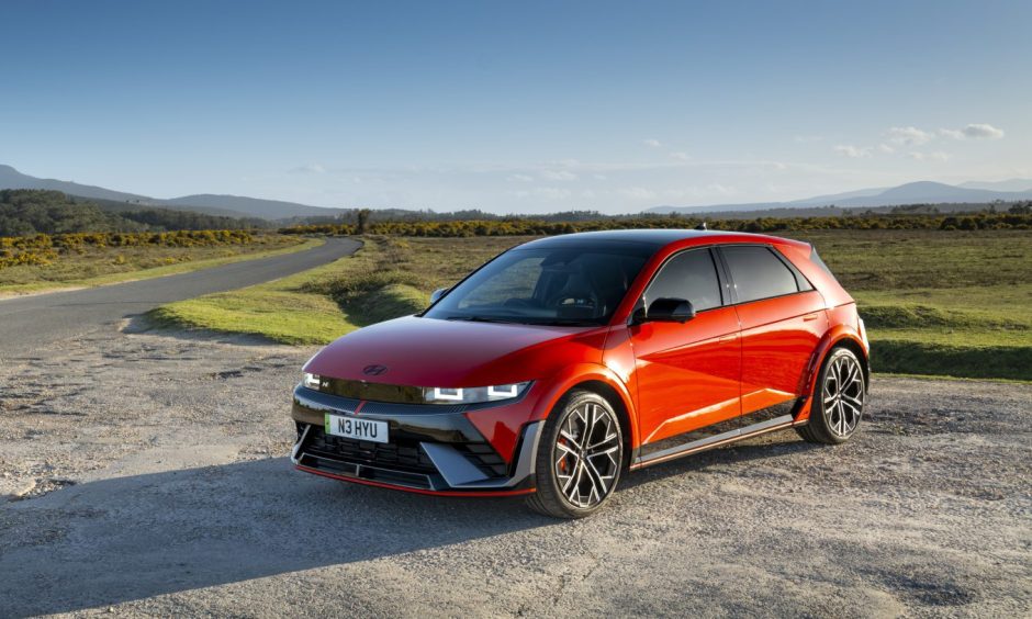 A red Ioniq 5 parked by the side of the road, with countryside in the background 