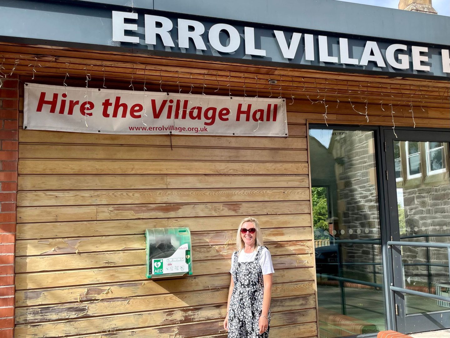 Kate Cox next to the defibrillator at Errol Village Hall