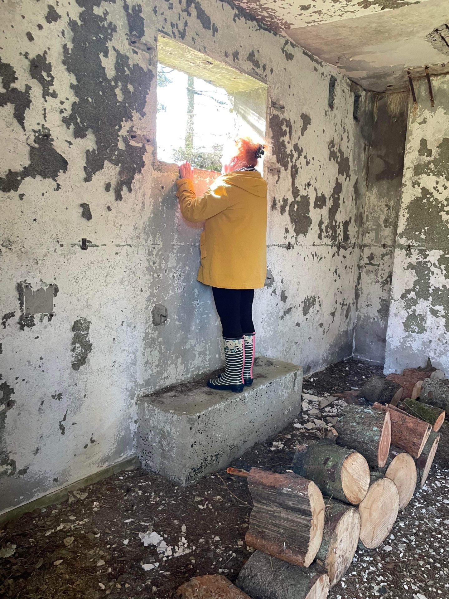 Margaret looks out of a window while standing inside a surviving structure at Downie Law.