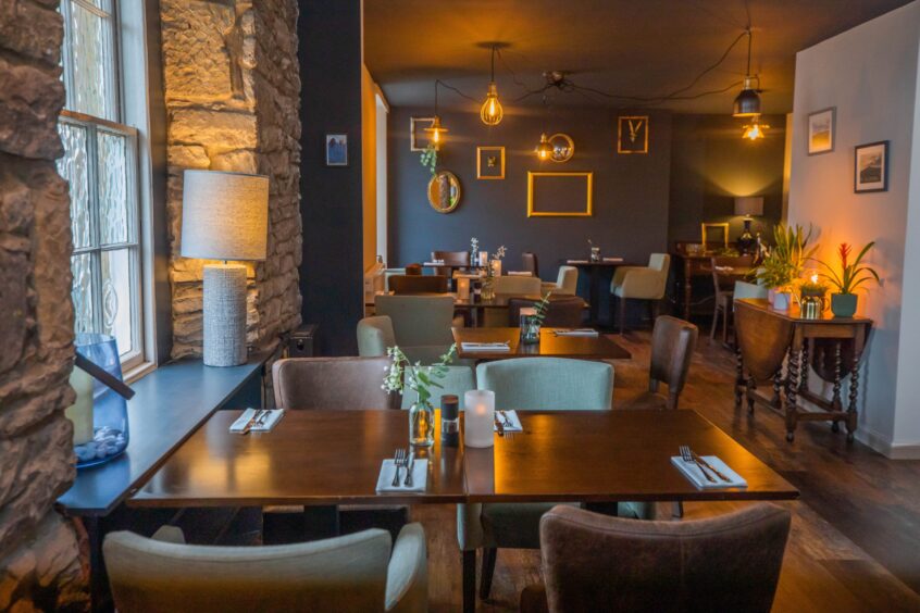 Dining area with old stone walls, blue and white painted walls and smart tables and chairs