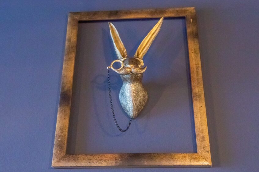 Brass frame with a brass model of a moustachioed hare wearing a monocle