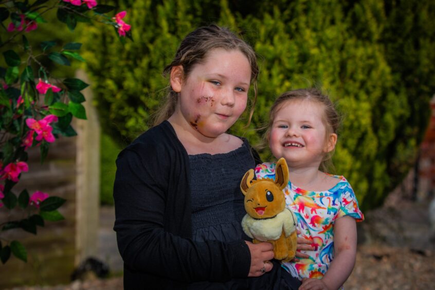 Alyssa MacDonald and her toddler sister seated in a pleasant garden