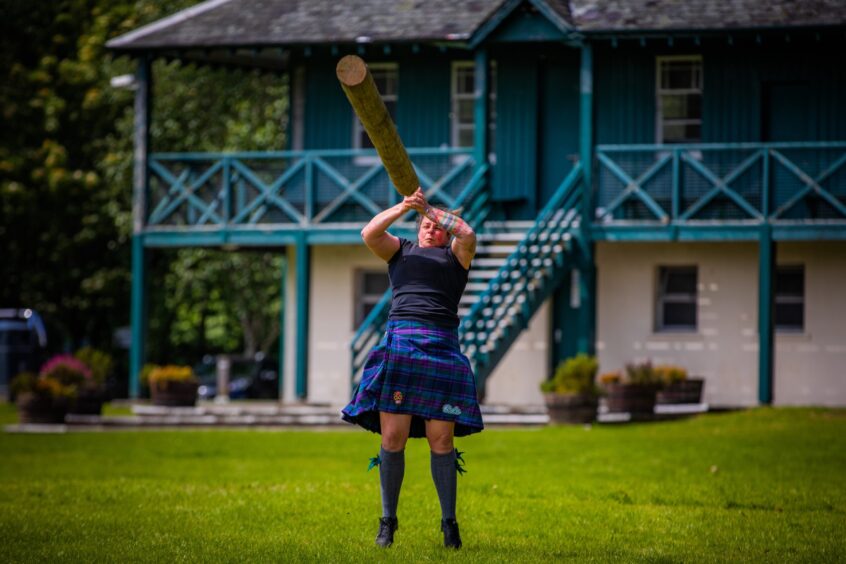 Person tossing caber in front of pavilion at Pitlochry Highland games field