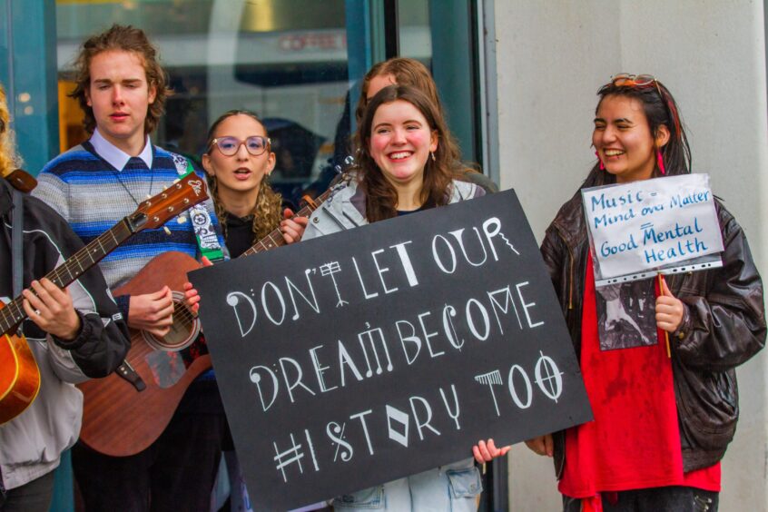 Protesters holding placards which read 'Don't let our dream become history too' and 'music - mind over matter - good mental health'