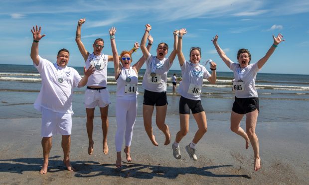 Finishers Alison, Catriona, Heather, Isabel, Jonny and Ryan celebrate in the sea and a jump at the Chariots of Fire Beach Race in St Andrews. Image: Steve Brown/DC Thomson
