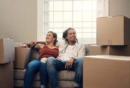 Happy couple sitting in a new home with boxes.