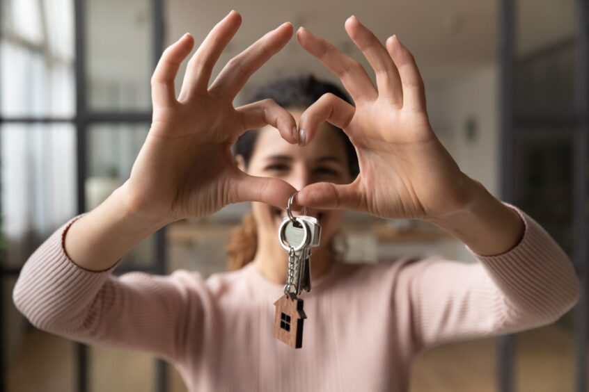 Woman making heart hands with key.