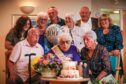 Hilda Stewart blowing out candles on birthday cake surrounded by family members