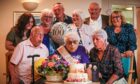 Hilda Stewart blowing out candles on birthday cake surrounded by family members