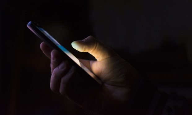 Man holding phone on dark background