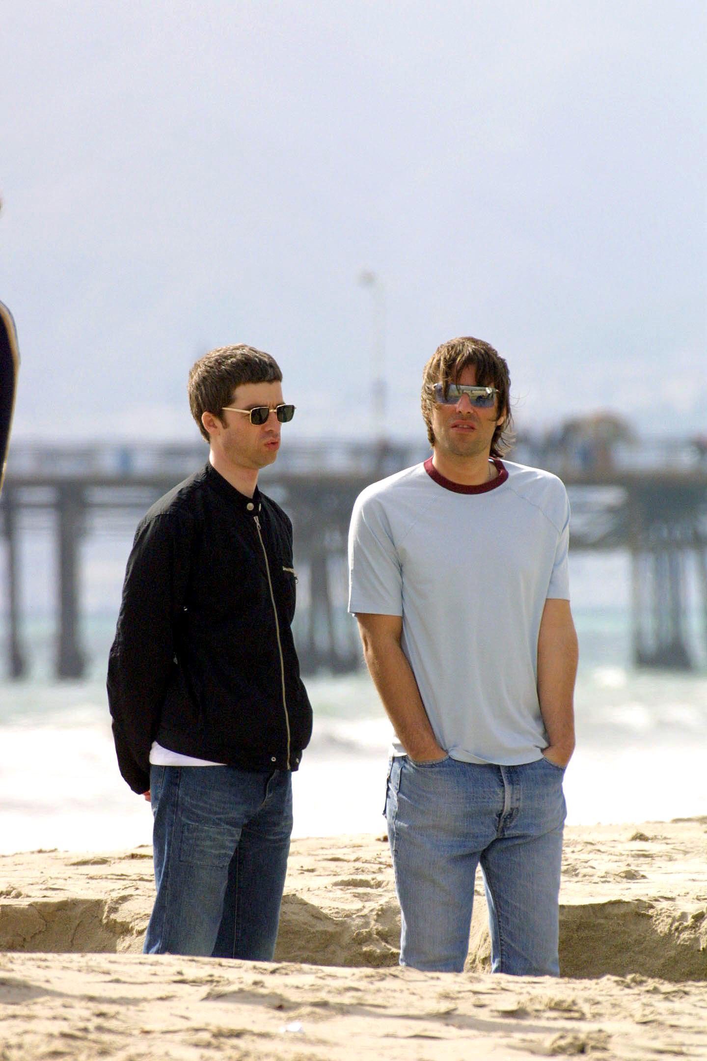 Noel and Liam Gallagher on a beach with a pier in the background in 2002. 